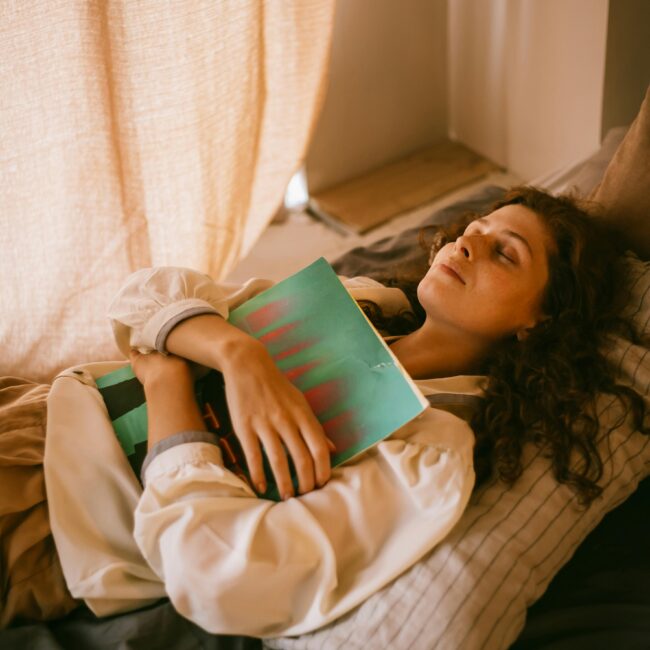 A teenager relaxing in a cozy bedroom while hugging a vinyl record, eyes closed.